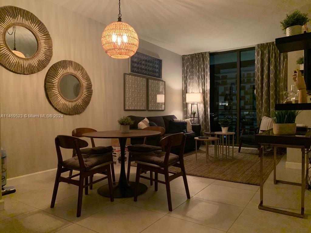 A dining area with a round table and chairs sits in front of a living room — 5350 NW 84th Ave # 1514, Doral FL 33166, DORAL, FL