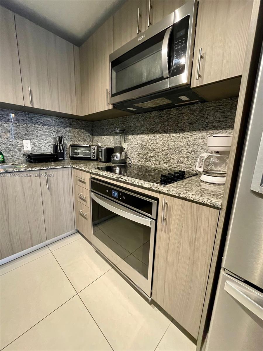 A kitchen features light wood cabinets, granite countertops, stainless steel appliances, and tile flooring — 5350 NW 84th Ave # 1514, Doral FL 33166, DORAL, FL