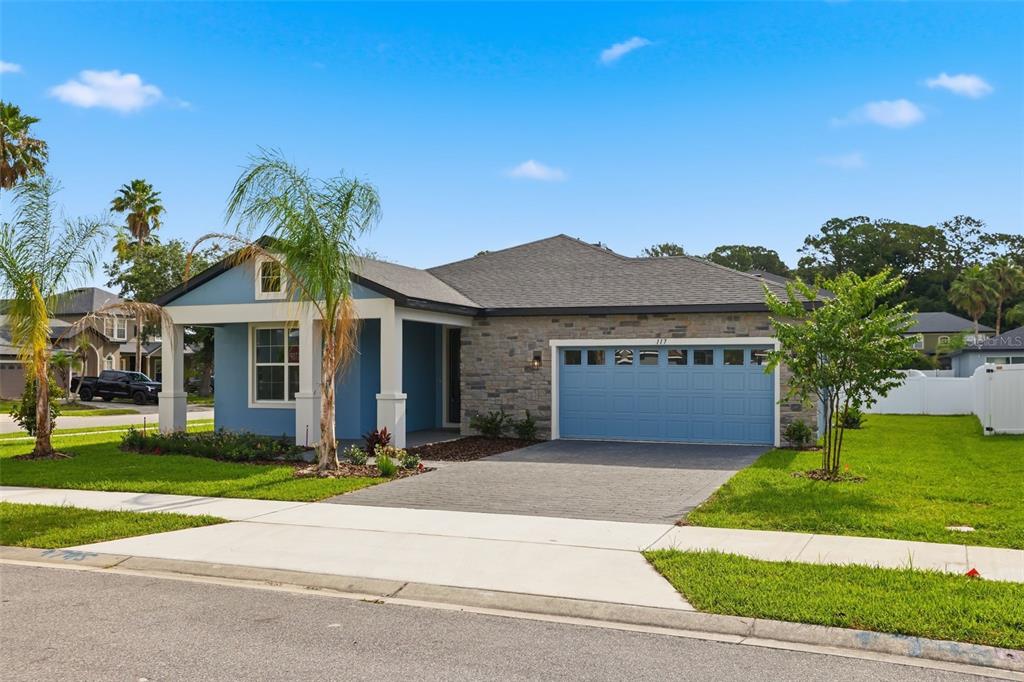 A blue single-story house with a stone facade, a two-car garage, and a front porch — 117 HADLEY DRIVE, SANFORD, FL