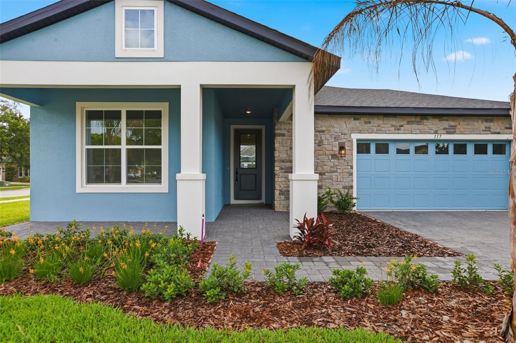 A blue house exterior with a stone facade, a covered entryway, and a garage — 117 HADLEY DRIVE, SANFORD, FL