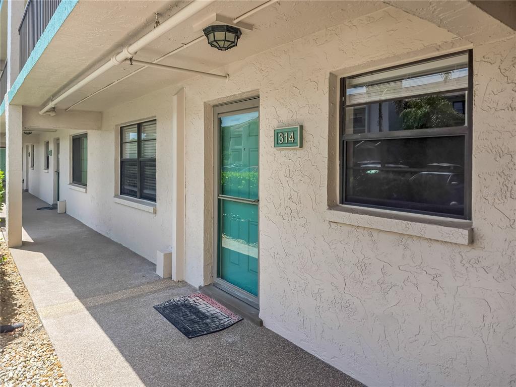 The exterior of a ground-level apartment unit features a teal front door numbered 314 — 175 KINGS HIGHWAY Bldg 3 UNIT 314, PUNTA GORDA, FL