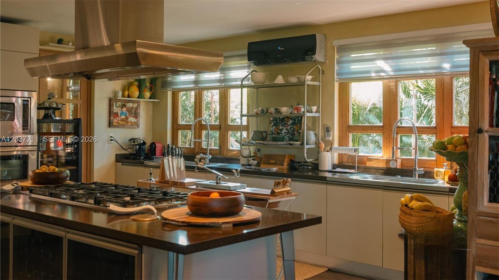 A kitchen features a large island with a gas cooktop, dark countertops, and wooden cabinetry — 0 Las iguanas, FL