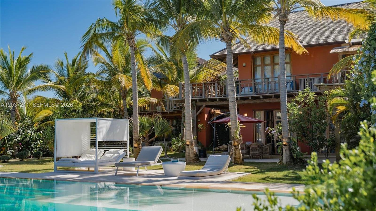 A swimming pool sits in front of a two-story house with palm trees and loungers — 0 Las iguanas, FL