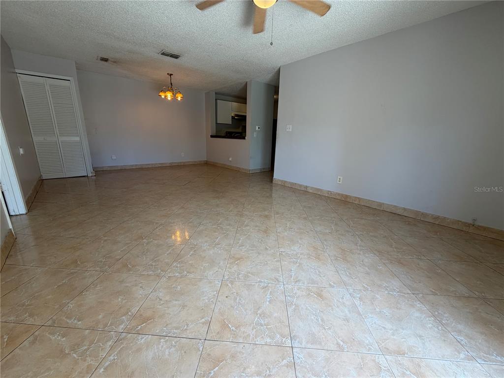 An open-concept living and dining area features light-colored tile flooring and a ceiling fan — 5225 VIA HACIENDA CIRCLE UNIT B115, ORLANDO, FL