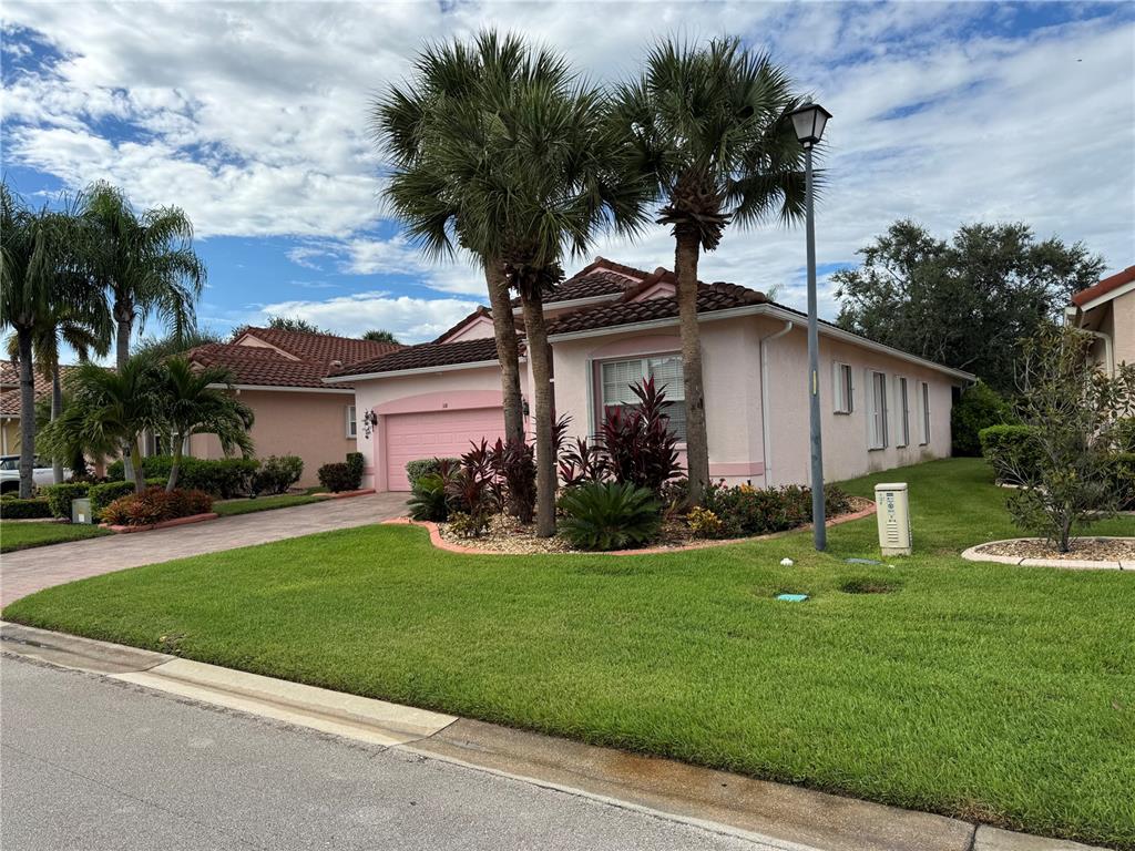 A pink single-story house with a tiled roof, palm trees, and a paved driveway — 318 NW SHOREVIEW DRIVE, PORT ST LUCIE, FL