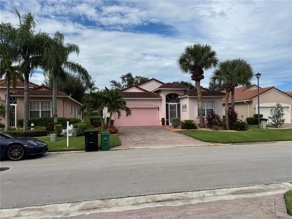 A pink, single-story suburban house with a tile roof, palm trees, and a paved driveway — 318 NW SHOREVIEW DRIVE, PORT ST LUCIE, FL