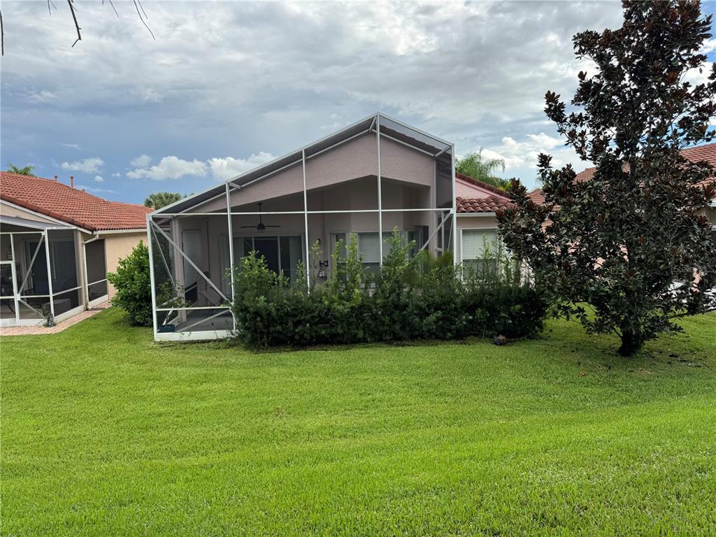 The exterior of a house features a screened-in patio and a large green lawn — 318 NW SHOREVIEW DRIVE, PORT ST LUCIE, FL