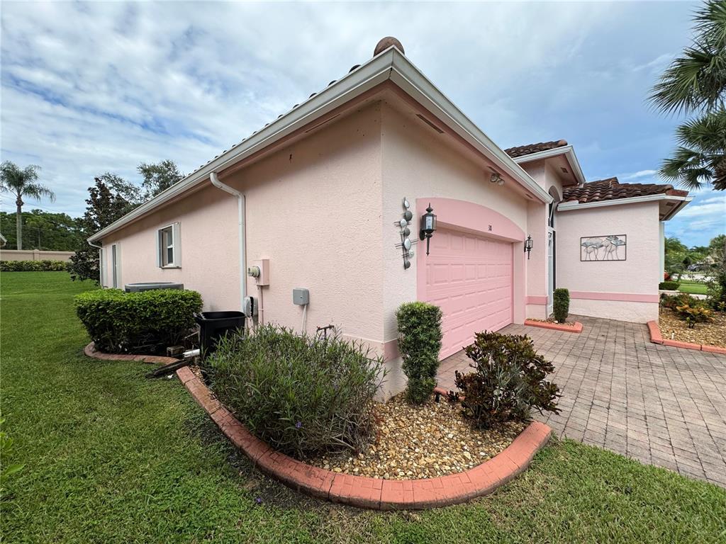 A pink stucco house exterior features a garage, a brick paver driveway, and landscaping — 318 NW SHOREVIEW DRIVE, PORT ST LUCIE, FL