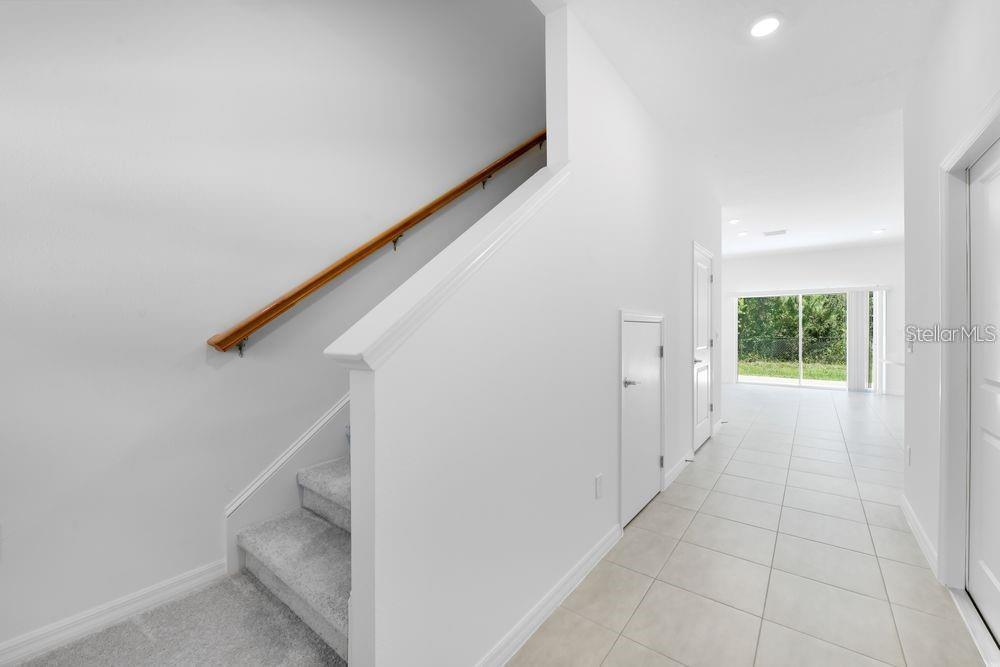 A bright entryway features a carpeted staircase with a wood handrail and tiled flooring — 15148 CUZCORRO COURT, NOKOMIS, FL