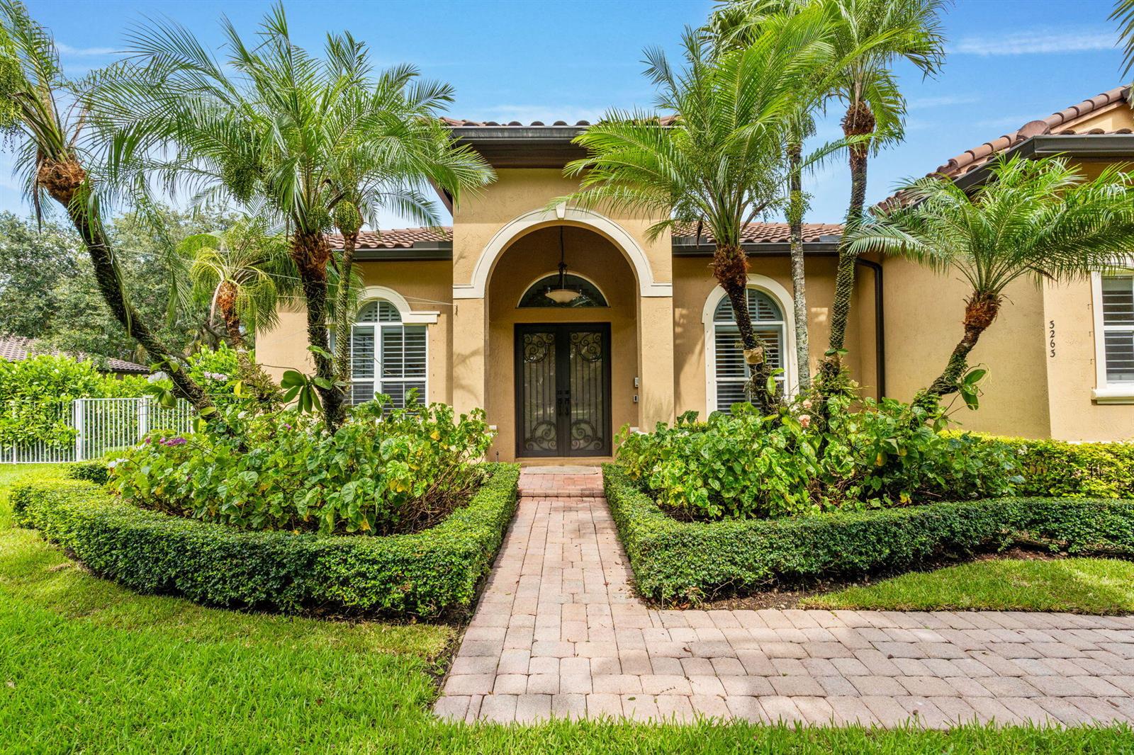 A tan stucco house with a brick walkway, arched entryway, and palm trees in front — 3263 SW 138th Way, Davie FL 33330, DAVIE, FL