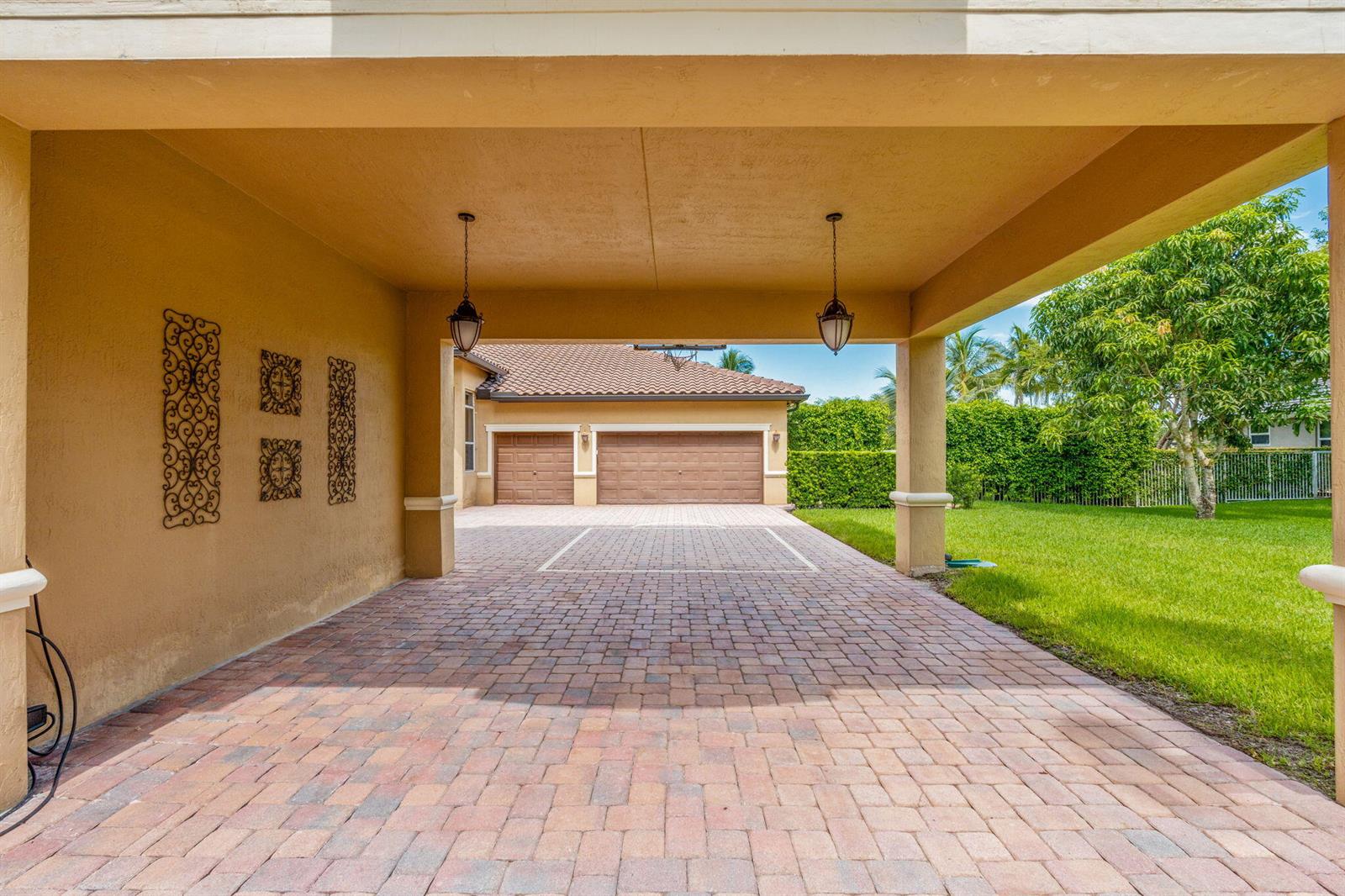 A covered brick paver driveway leads to a two-car garage with tan stucco walls — 3263 SW 138th Way, Davie FL 33330, DAVIE, FL
