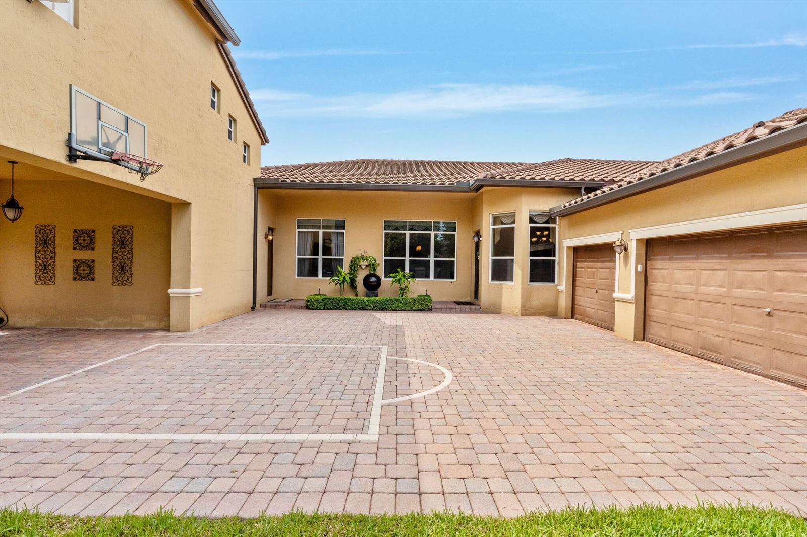 A paved driveway features a basketball hoop and garage doors in front of a house — 3263 SW 138th Way, Davie FL 33330, DAVIE, FL