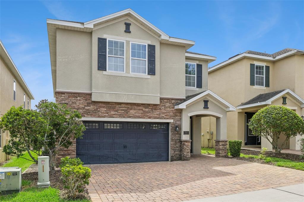A two-story house with a stone-accented facade, a two-car garage, and a paved driveway — 341 PENDANT COURT, KISSIMMEE, FL
