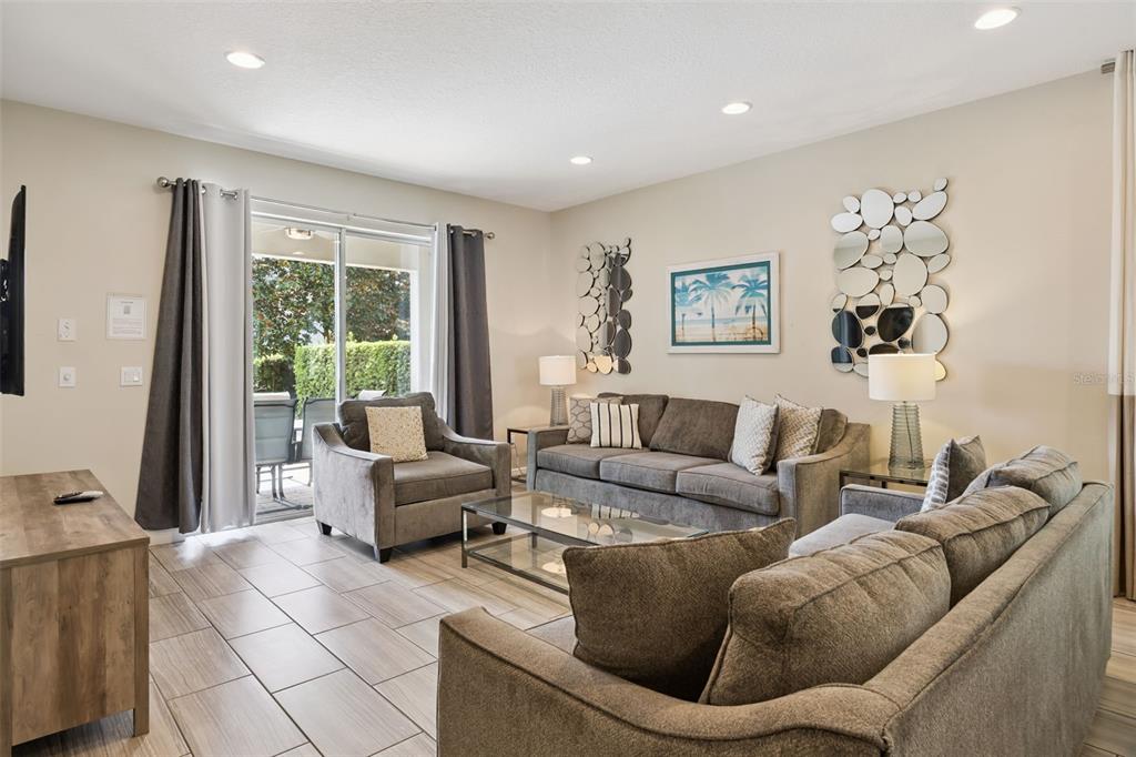 A living room features gray sofas, a glass coffee table, tile floors, and sliding glass doors — 341 PENDANT COURT, KISSIMMEE, FL