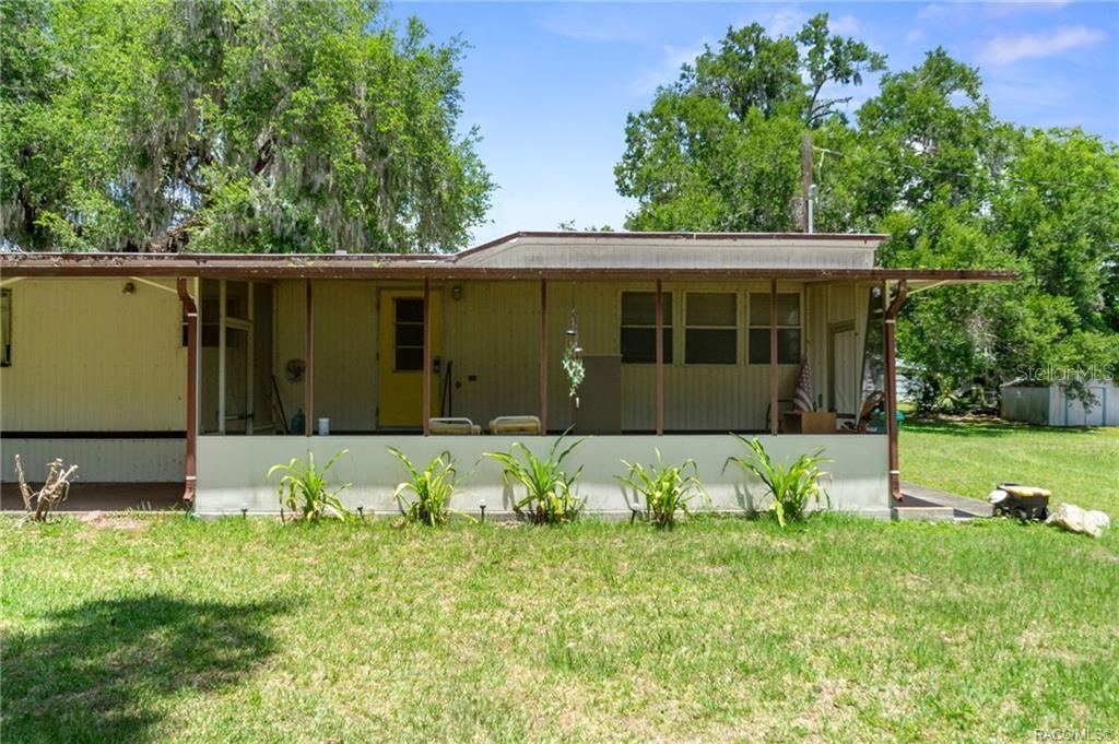 A single-story house with a screened-in porch and a yellow door sits on a lawn — 8845 E WASHINGTON LANE, FLORAL CITY, FL