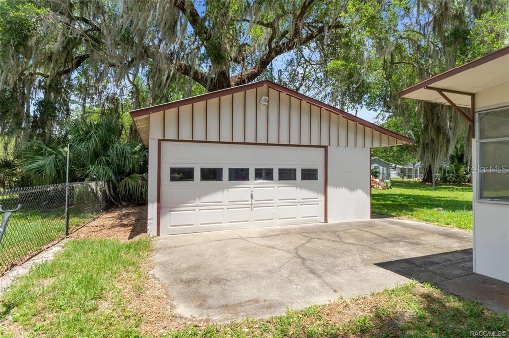 A detached garage with a white sectional door sits on a concrete driveway — 8845 E WASHINGTON LANE, FLORAL CITY, FL