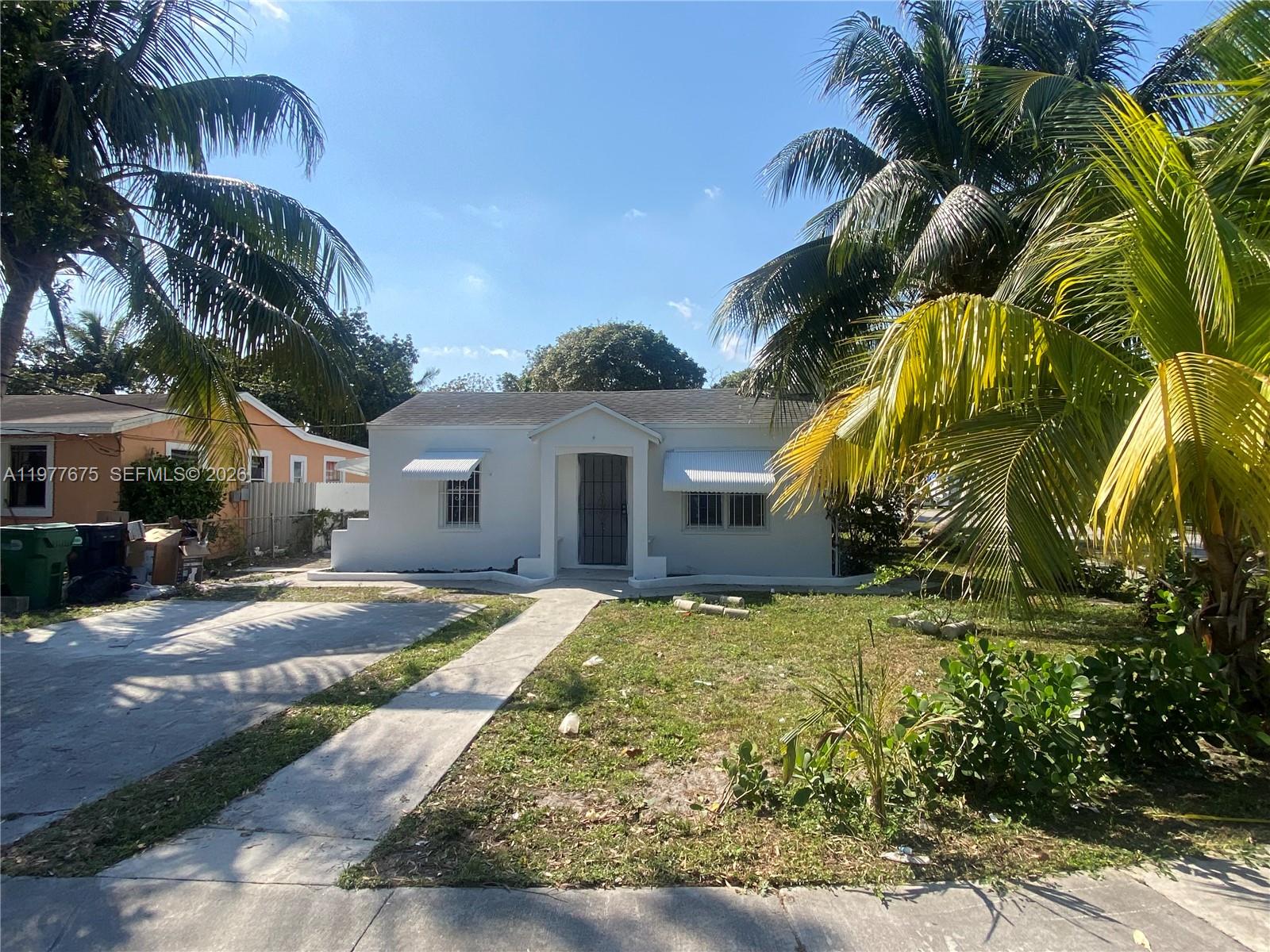 A white, single-story house with metal window awnings sits behind a palm-lined front yard — 894 NW 108th St # 1, Miami FL 33168, MIAMI, FL