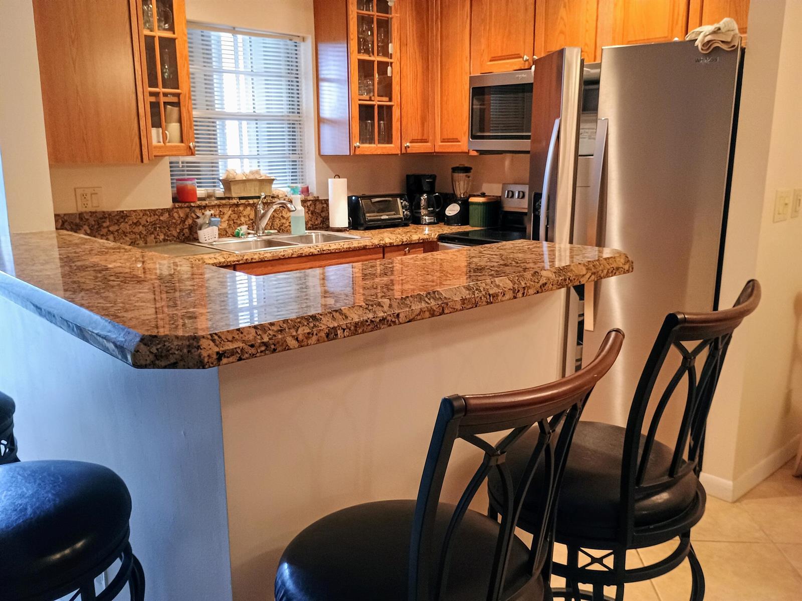 A kitchen features wood cabinets, granite countertops, stainless steel appliances, and a breakfast bar — 14716 Canalview Drive # D, Delray Beach FL 33484, DELRAY BEACH, FL