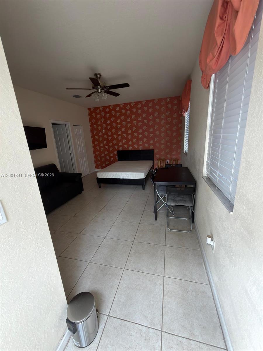 A studio apartment features tile flooring, a bed, a dining table, and a patterned wall — 16961 SW 90th Ter, Miami FL 33196, MIAMI, FL