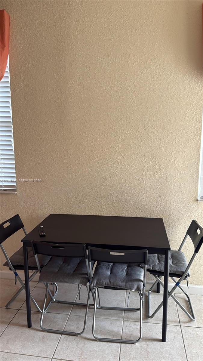A dining area features a dark rectangular table with four folding chairs on tiled flooring — 16961 SW 90th Ter, Miami FL 33196, MIAMI, FL
