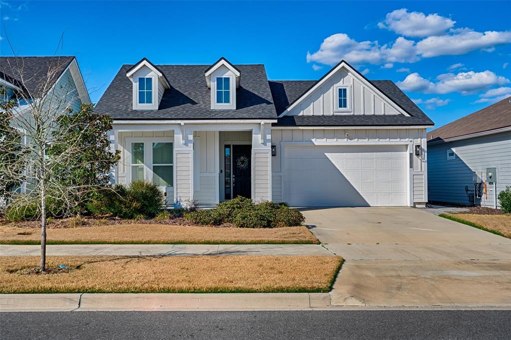 A white house with a two-car garage, dormer windows, and a dark shingled roof — 12020 SW 30TH AVENUE, GAINESVILLE, FL
