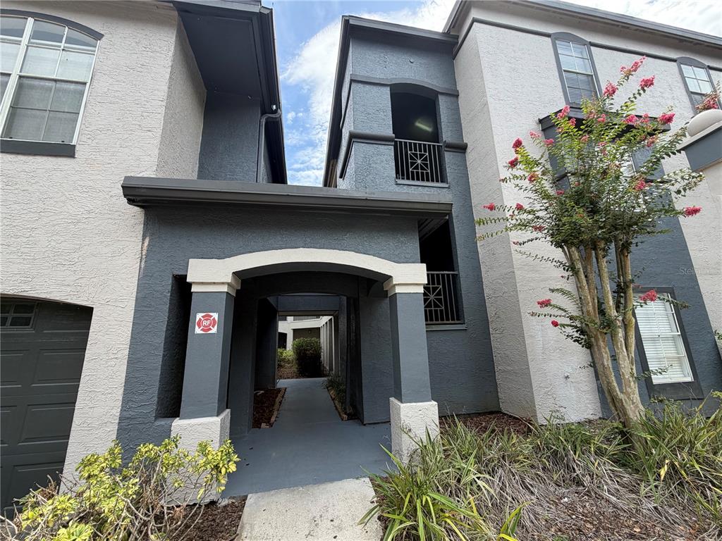 A multi-story apartment building exterior features a covered walkway entrance with a fire safety sign — 13210 ARBOR ISLE DR UNIT 102, TEMPLE TERRACE, FL