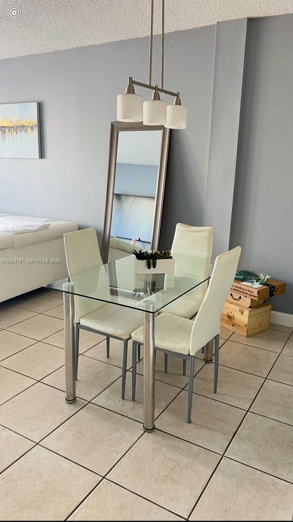 A dining area features a glass table, four white chairs, and a floor mirror — 10900 SW 104th St # 219, Miami FL 33176, MIAMI, FL