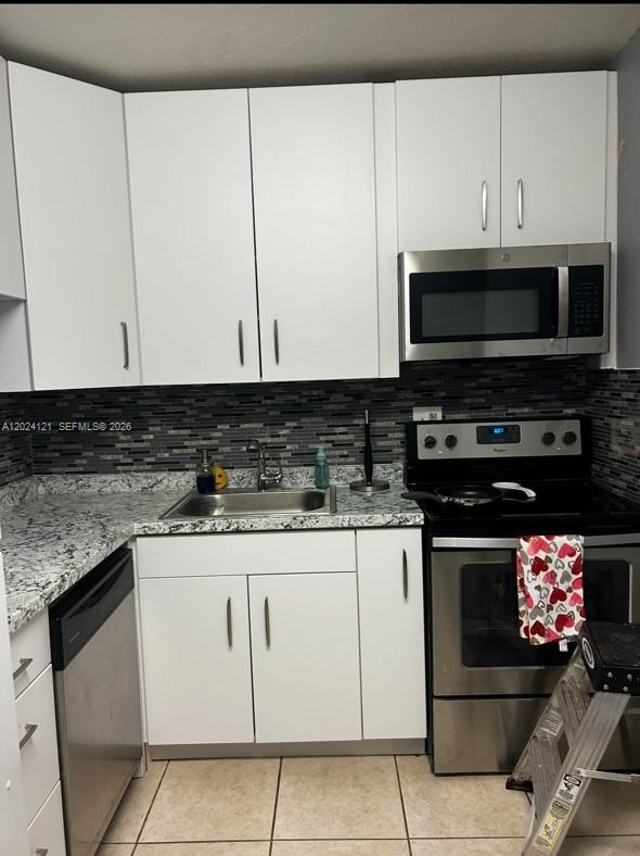 A kitchen features white cabinets, granite countertops, stainless steel appliances, and a dark tiled backsplash — 10900 SW 104th St # 219, Miami FL 33176, MIAMI, FL
