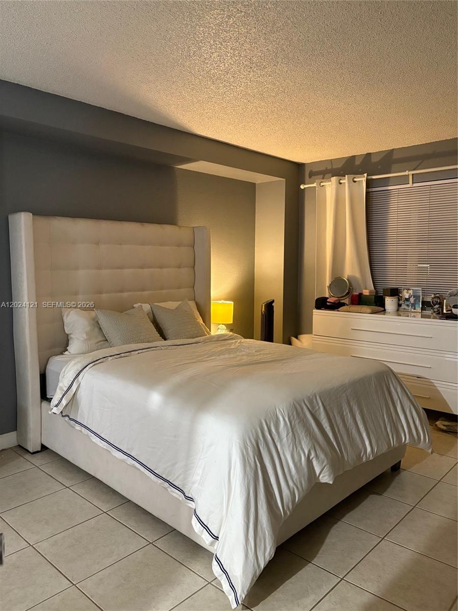 A bedroom features a tufted upholstered headboard, white bedding, and a white dresser — 10900 SW 104th St # 219, Miami FL 33176, MIAMI, FL