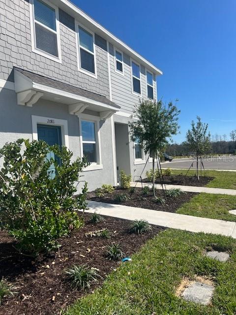 A gray two-story townhouse exterior features a front door, windows, and a small landscaped yard — 2081 VIEWFINDER ST, KISSIMMEE, FL