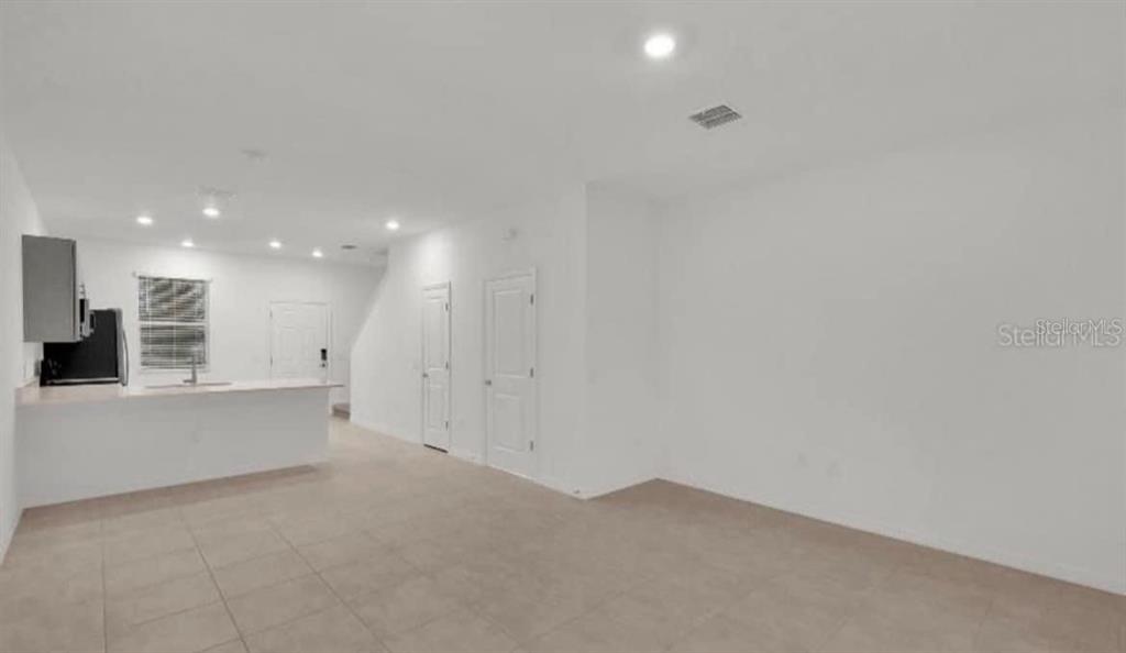 An open-concept living area features a kitchen with a breakfast bar and tiled flooring — 2081 VIEWFINDER ST, KISSIMMEE, FL