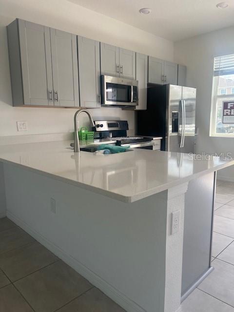 A kitchen features light gray cabinets, stainless steel appliances, and a white quartz island countertop — 2081 VIEWFINDER ST, KISSIMMEE, FL