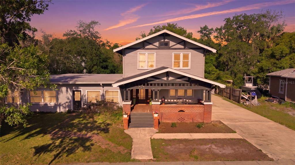 A two-story house with gray siding, a brick porch, and a flat-roofed side addition — 812 SANFORD AVENUE, SANFORD, FL