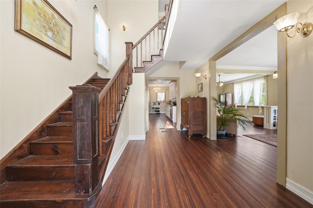 A foyer with dark wood flooring features a wooden staircase and an open living area — 812 SANFORD AVENUE, SANFORD, FL