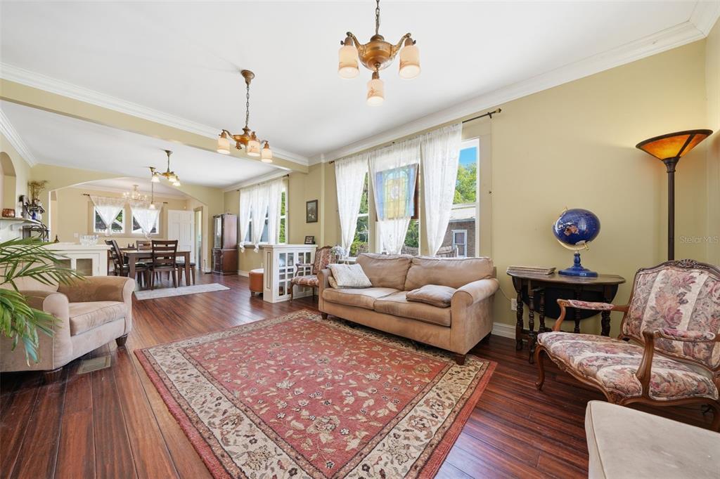 A living room with hardwood floors, a patterned area rug, and a dining area beyond — 812 SANFORD AVENUE, SANFORD, FL