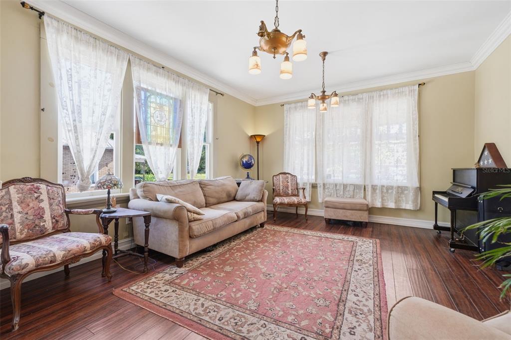 A living room features hardwood floors, a large area rug, a sofa, and two chandeliers — 812 SANFORD AVENUE, SANFORD, FL