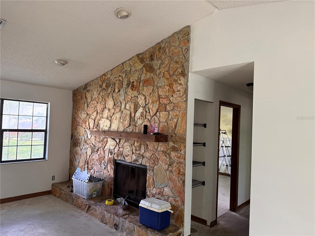 A living room features a stone fireplace, vaulted ceiling, and sliding glass doors to outside — 3625 NE 18TH COURT, OCALA, FL