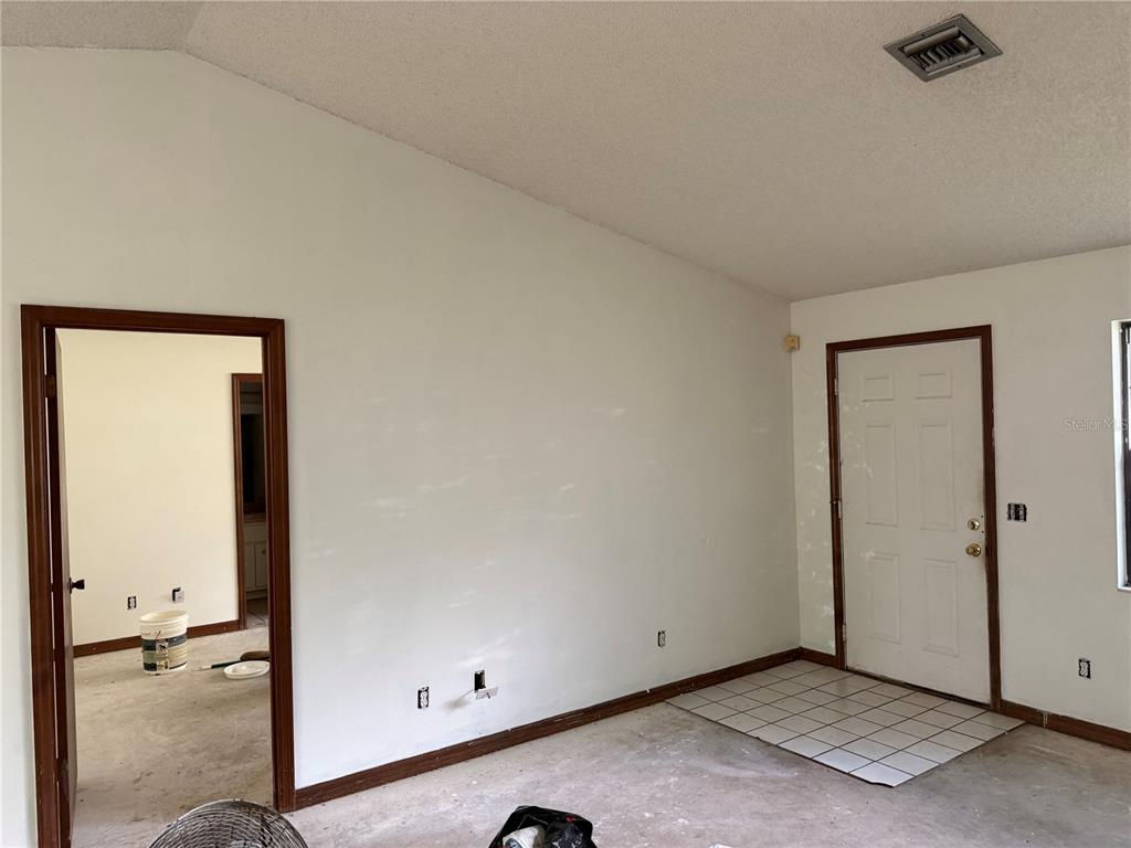 An empty living room features a stone fireplace, white walls, and a tiled entryway — 3625 NE 18TH COURT, OCALA, FL