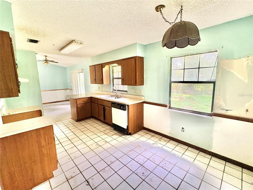 A living room features a stone fireplace, vaulted ceilings, and an adjacent kitchen area — 3625 NE 18TH COURT, OCALA, FL
