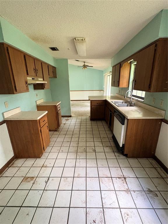 A kitchen with wood cabinets and tile flooring opens to a living area with concrete floors — 3625 NE 18TH COURT, OCALA, FL