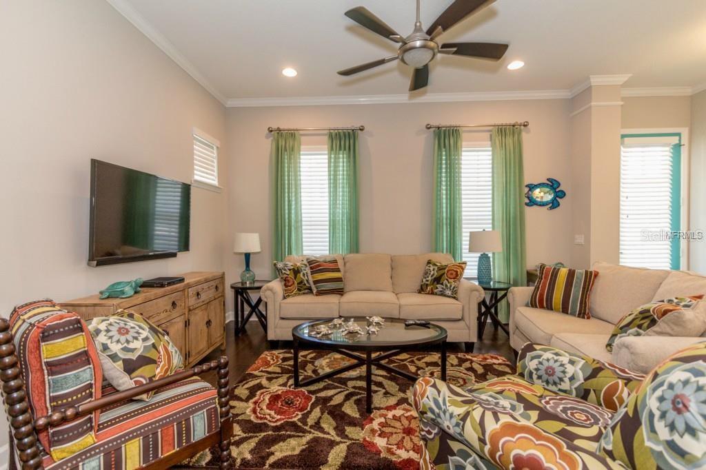 A kitchen features white cabinets, granite countertops, stainless steel appliances, and a teal pantry door — 1596 CASTILE STREET, CELEBRATION, FL