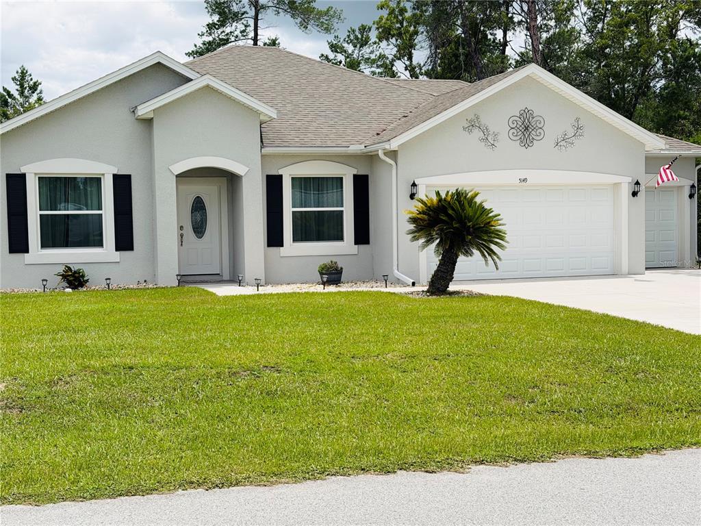 A single-story house with a gray stucco exterior, black shutters, and a two-car garage — 5149 SW 107TH LOOP, OCALA, FL