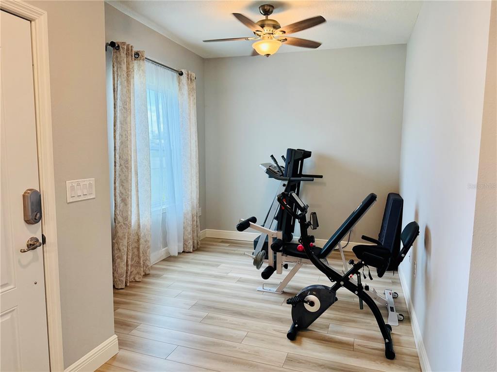 A room with light wood-look flooring, a ceiling fan, and a home gym machine — 5149 SW 107TH LOOP, OCALA, FL