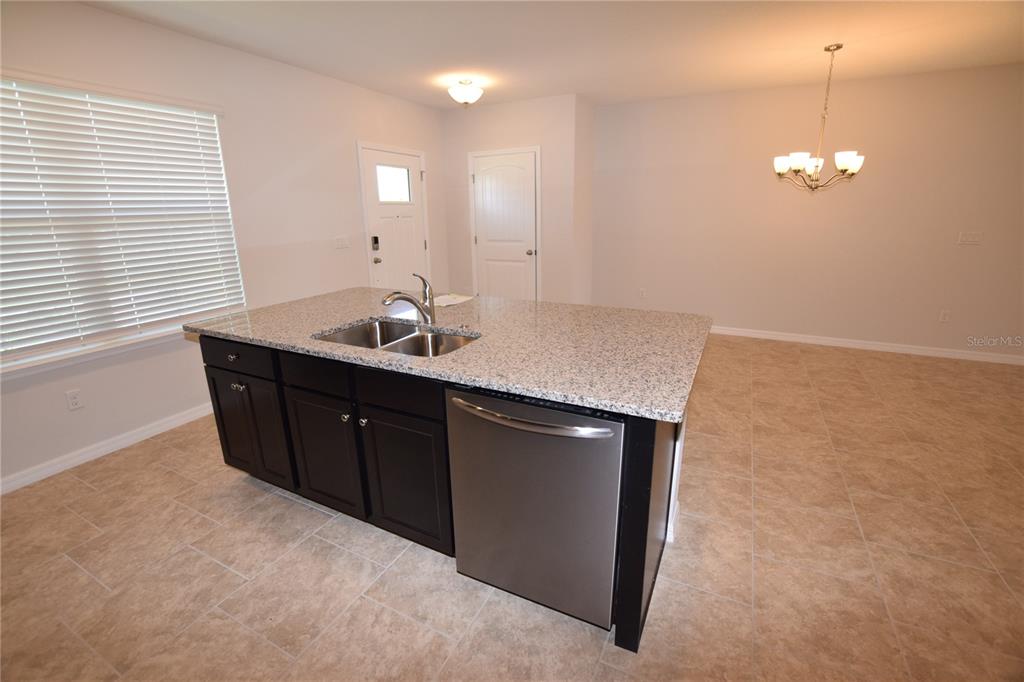 A kitchen island with a stainless steel dishwasher and sink sits in a tiled room — 9496 BAUER ALLEY, WINTER GARDEN, FL