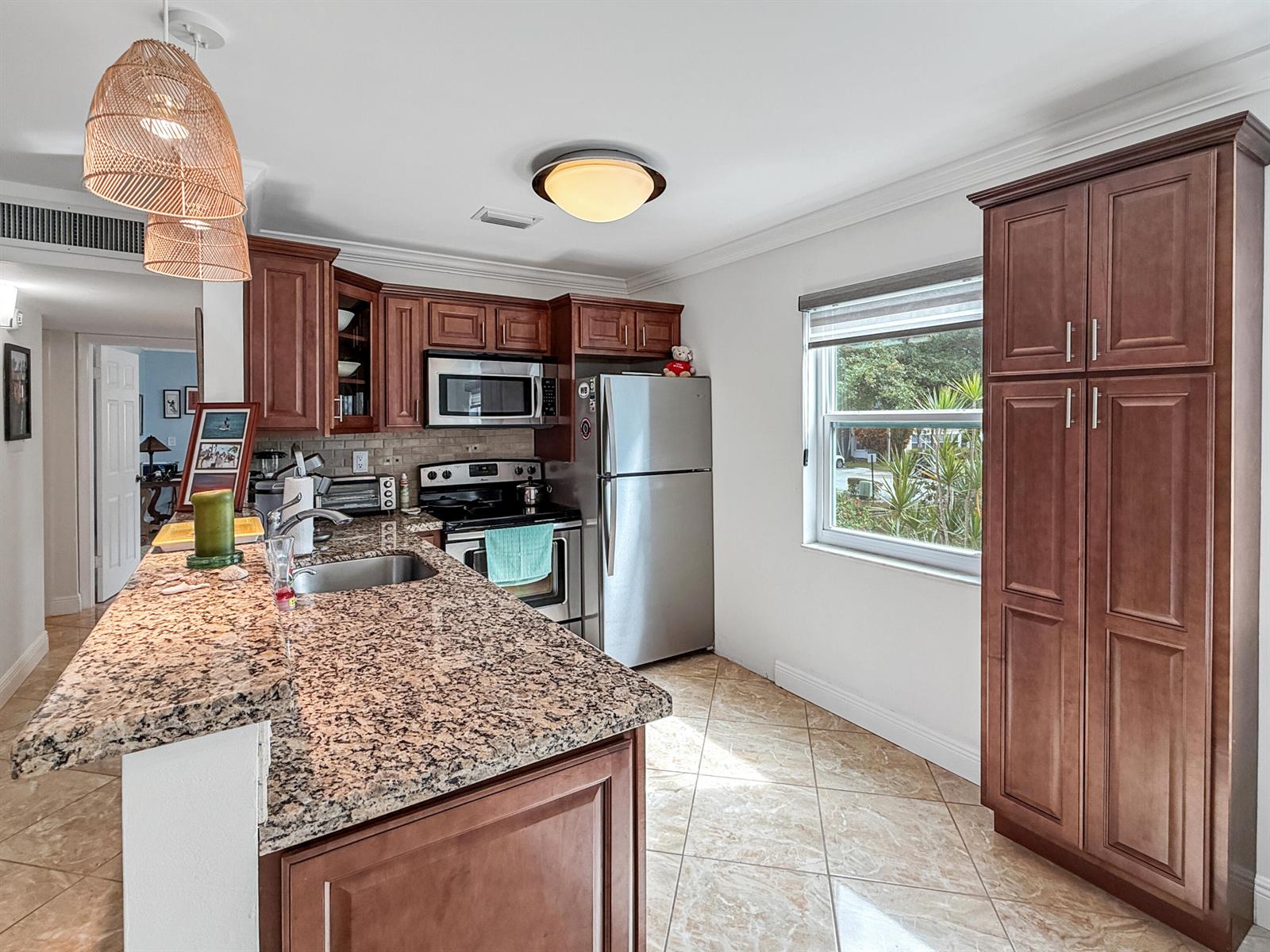 A kitchen features granite countertops, stainless steel appliances, dark wood cabinets, and tile flooring — 334 Piedmont G, Delray Beach FL 33484, DELRAY BEACH, FL