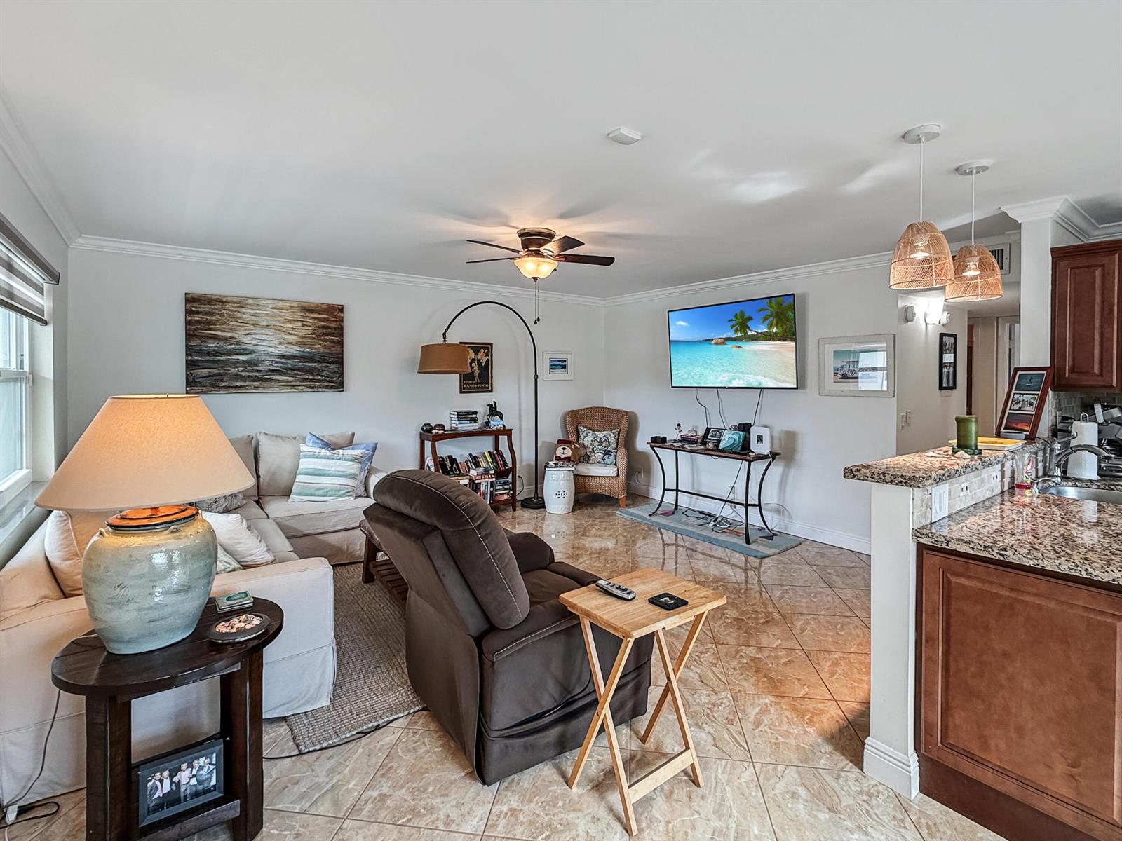 A living room features tile flooring, a ceiling fan, a wall-mounted television, and adjacent kitchen — 334 Piedmont G, Delray Beach FL 33484, DELRAY BEACH, FL