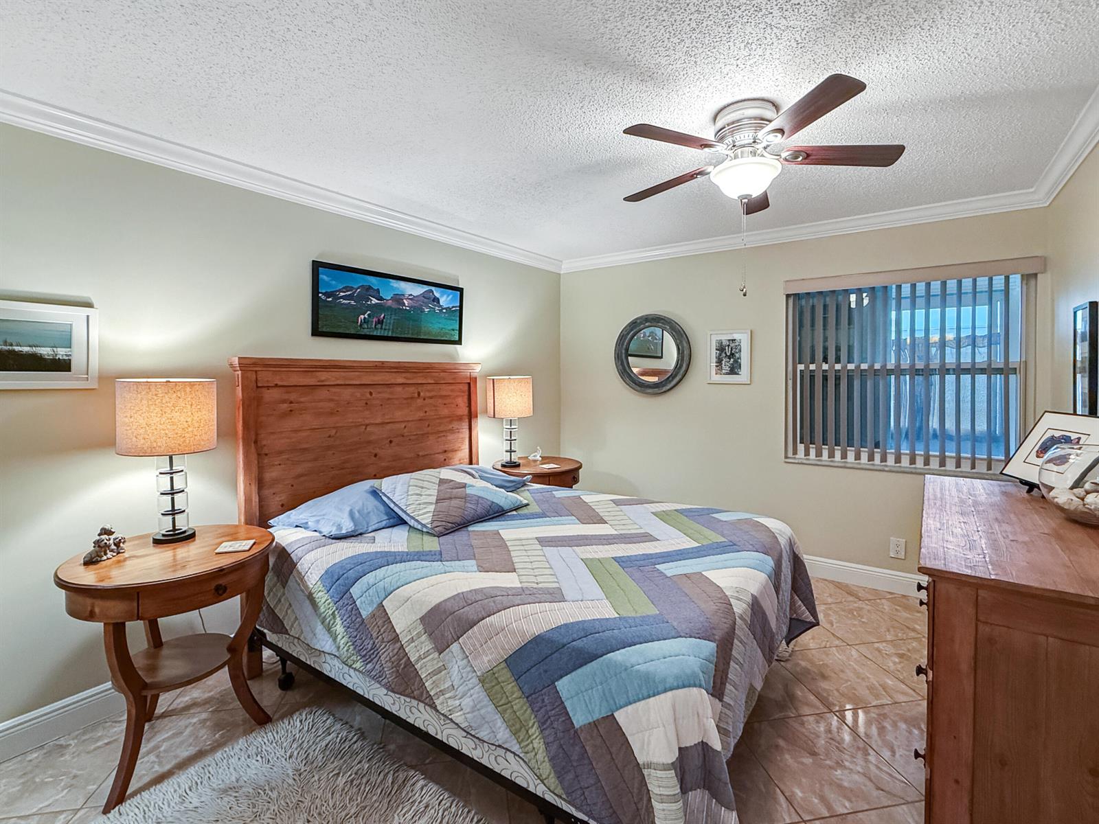 A bedroom features a wooden bed frame, a patterned quilt, and tile flooring — 334 Piedmont G, Delray Beach FL 33484, DELRAY BEACH, FL