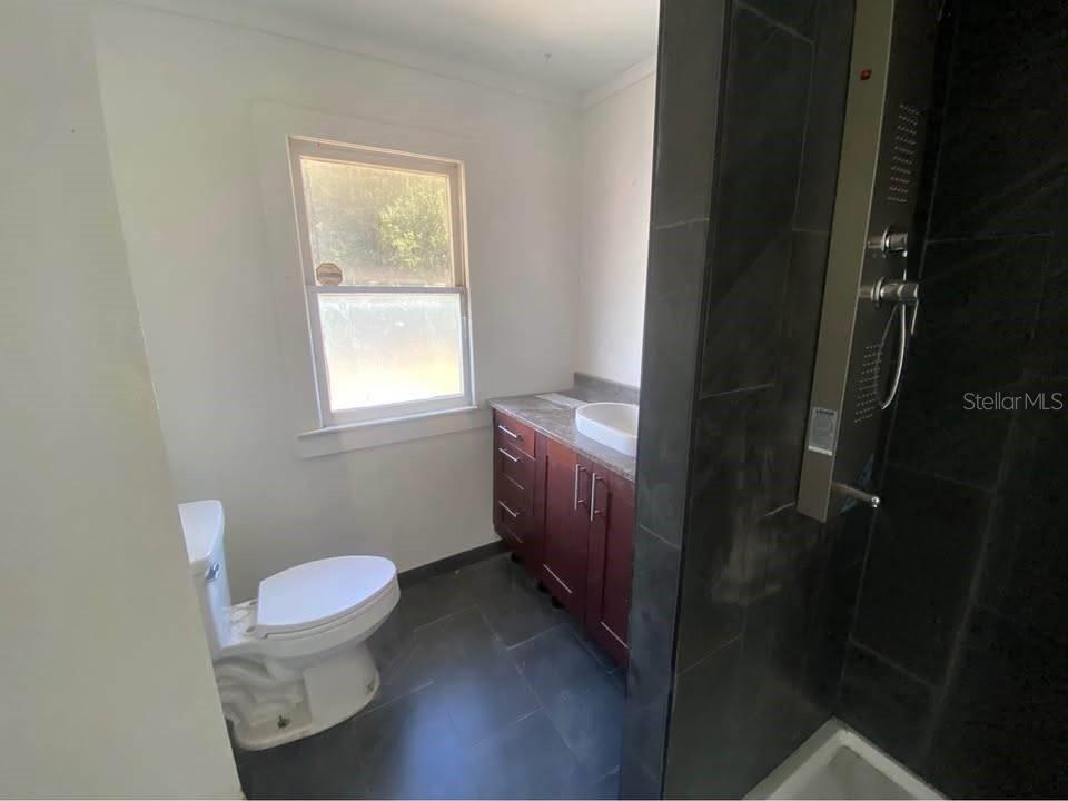 A bathroom with a toilet, a dark wood vanity, and a tiled shower stall — 1254 PINEY ROAD, NORTH FORT MYERS, FL