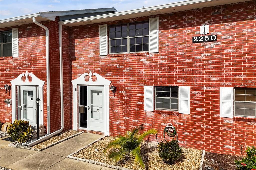 A red brick building exterior features two white front doors and white-shuttered windows — 2250 S PALMETTO AVENUE UNIT i-11, DAYTONA BEACH, FL