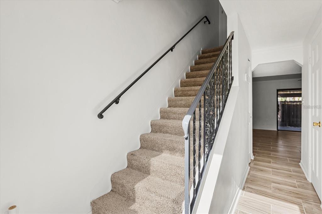A carpeted staircase with a black metal railing and handrail leads to an upper floor — 2250 S PALMETTO AVENUE UNIT i-11, DAYTONA BEACH, FL